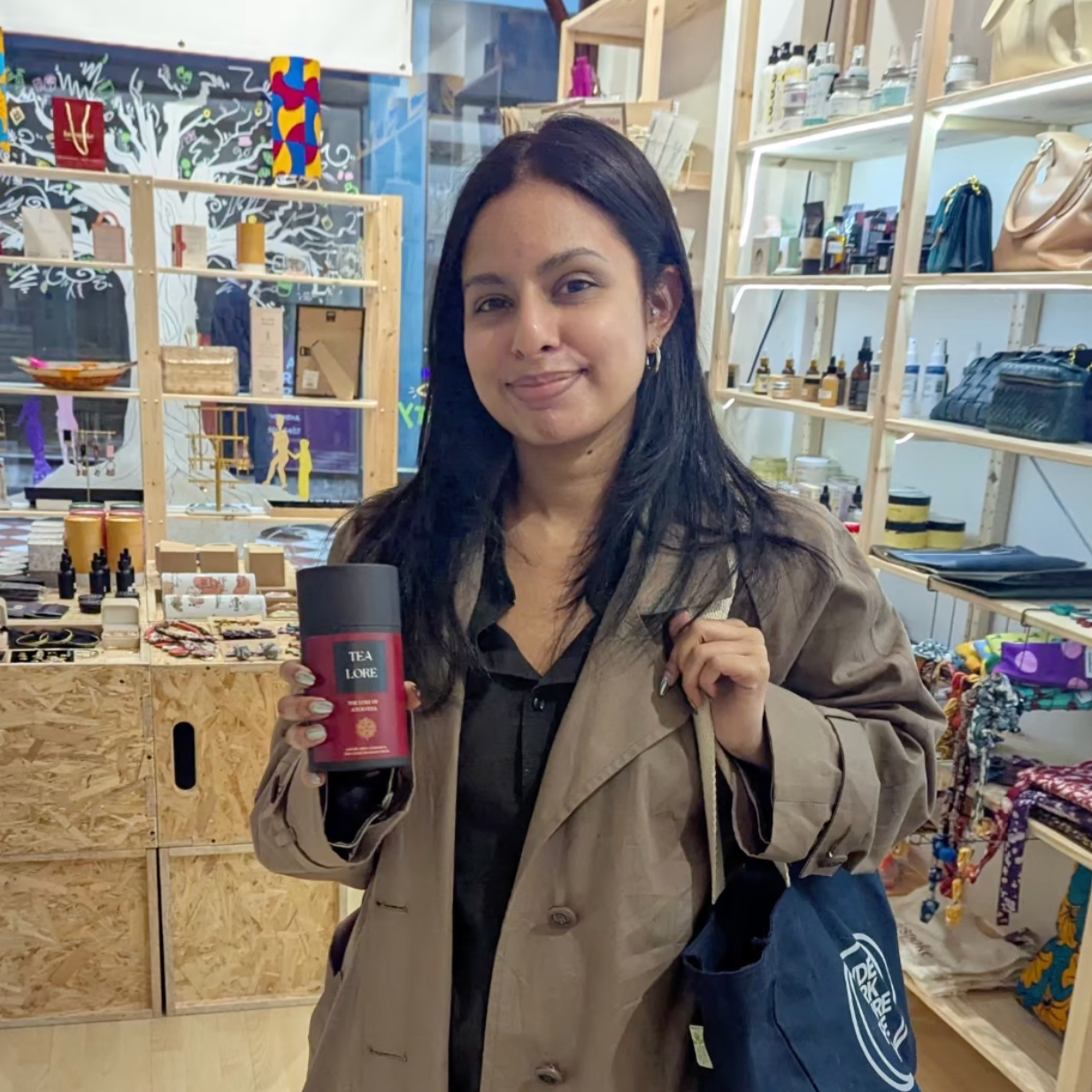 Woman holding a red tea packet and a blue bag in a store setting