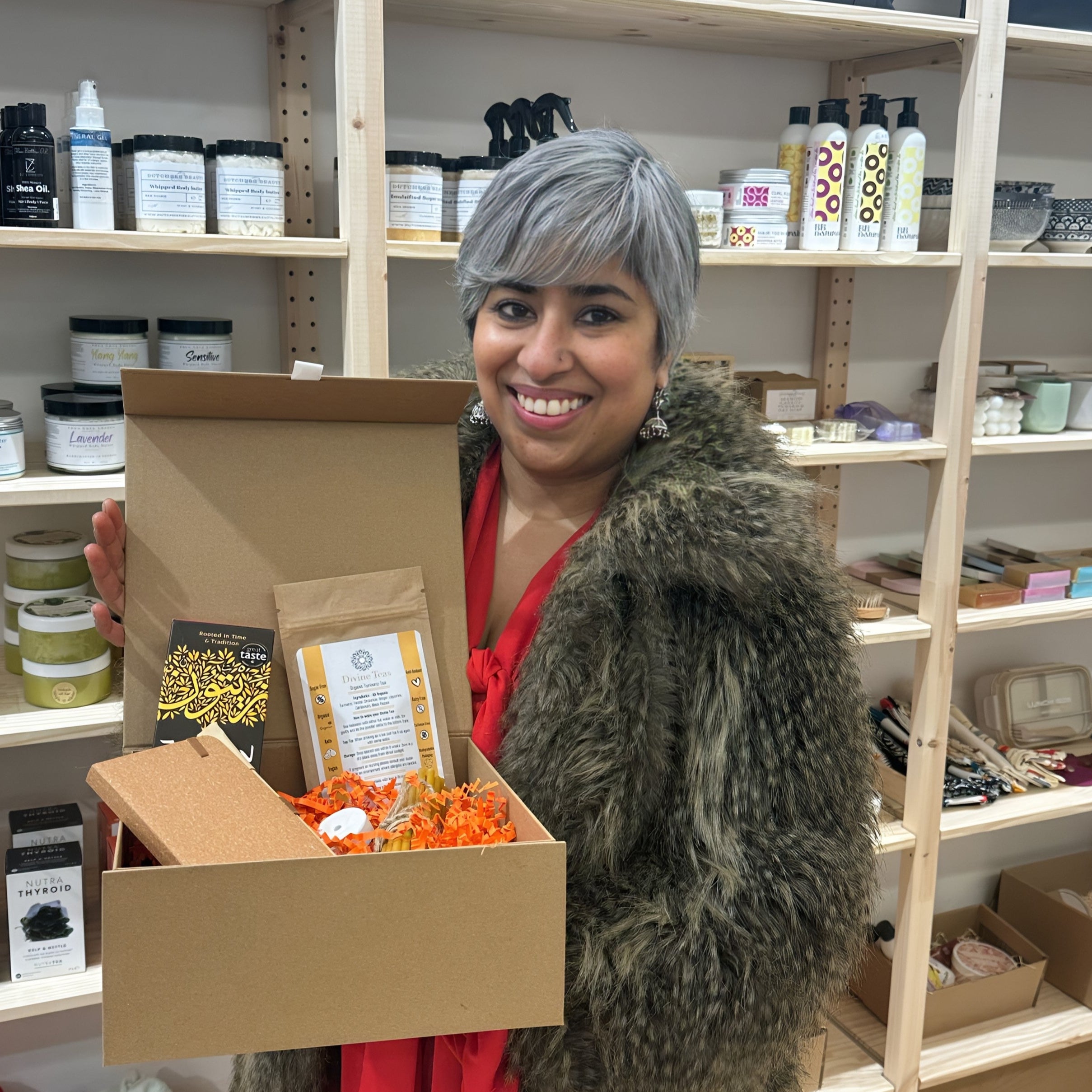 Woman holding a box of products in a store setting Divine Teas